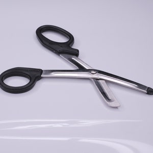May include: Black handled bandage scissors with a silver blade. The scissors are open and ready to cut.