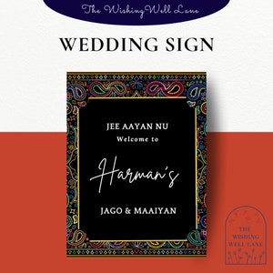 May include: A black wedding sign with a colorful paisley border. The sign reads "Jee Aayan Nu Welcome to Harman's Jago & Maaiyan".