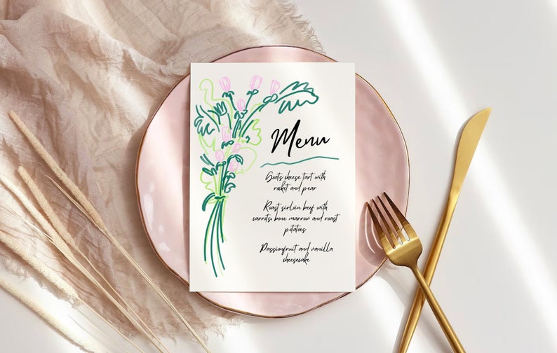 May include: A white menu card with a green and pink line drawing of flowers on the left side. The text "Menu" is written in black cursive on the right side. The menu lists "Goats cheese tart with rocket and pear", "Roast sirloin beef with carrots bone marrow and roast potatoes", and "Passionfruit and vanilla cheesecake".