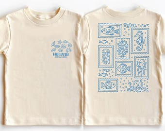 May include: Cream-colored t-shirt with blue sea-themed graphics. The front features a cluster of sea creatures and text that reads "WHITE FAMILY Summer 2026." The back displays various sea creatures in stamp-like designs.