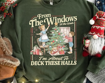 May include: Dark green sweatshirt with a Christmas-themed graphic. The graphic features a vintage illustration of children decorating a Christmas tree, with the text "From The Windows To The Walls I'm About To Deck These Halls."