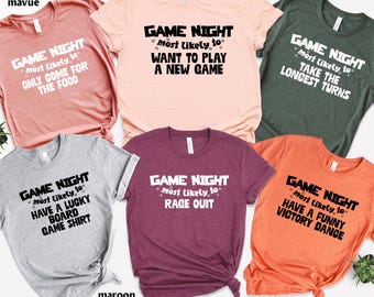 May include: A collection of six t-shirts in various colors, including peach, forest green, and maroon. Each shirt features the text "GAME NIGHT" with a humorous phrase such as "ONLY COME FOR THE FOOD" or "RAGE QUIT".