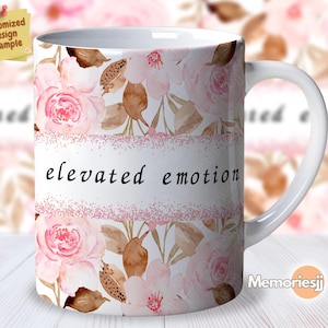 Puede incluir: Taza de cerámica blanca con un diseño floral rosa y el texto "elevated emotion" en letras negras. La taza tiene un asa y está decorada con una franja de purpurina rosa.