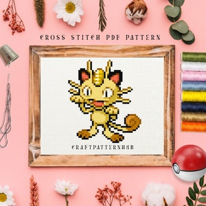 May include: Cross stitch pattern of a yellow and brown Pokemon character, Eevee, in a wooden frame. The pattern is titled "CRAFTPATTERNHUB".