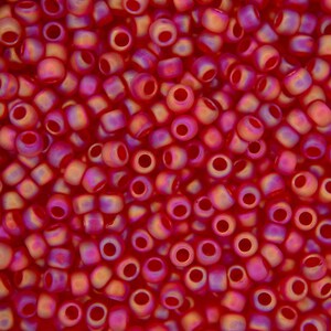 Peut inclure: Gros plan sur une grande quantité de petites perles de verre rondes, rouges et orange irisées. Les perles ont une finition lisse et brillante.