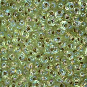 Op de afbeelding: Close-up van een stapel iriserende groene glazen kralen. Elke kraal heeft een centraal gat en een glanzend, reflecterend oppervlak. De kralen zijn klein en rond, ideaal voor het maken van sieraden of knutselen.