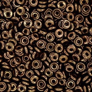 May include: A close-up image of a pile of small, round, metallic bronze beads. The beads have a hole in the centre and a shiny, reflective surface.