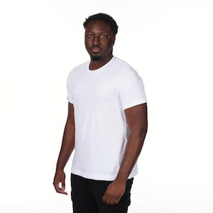 May include: A white crew neck t-shirt with short sleeves. The t-shirt is plain and has a simple design. The person in the image is wearing black pants. The background is white.