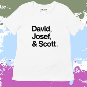 May include: White t-shirt with the names "David, Josef, & Scott" printed in black. The shirt has a crew neck and short sleeves. The brand logo "LIVE NIR" is printed on the upper chest.