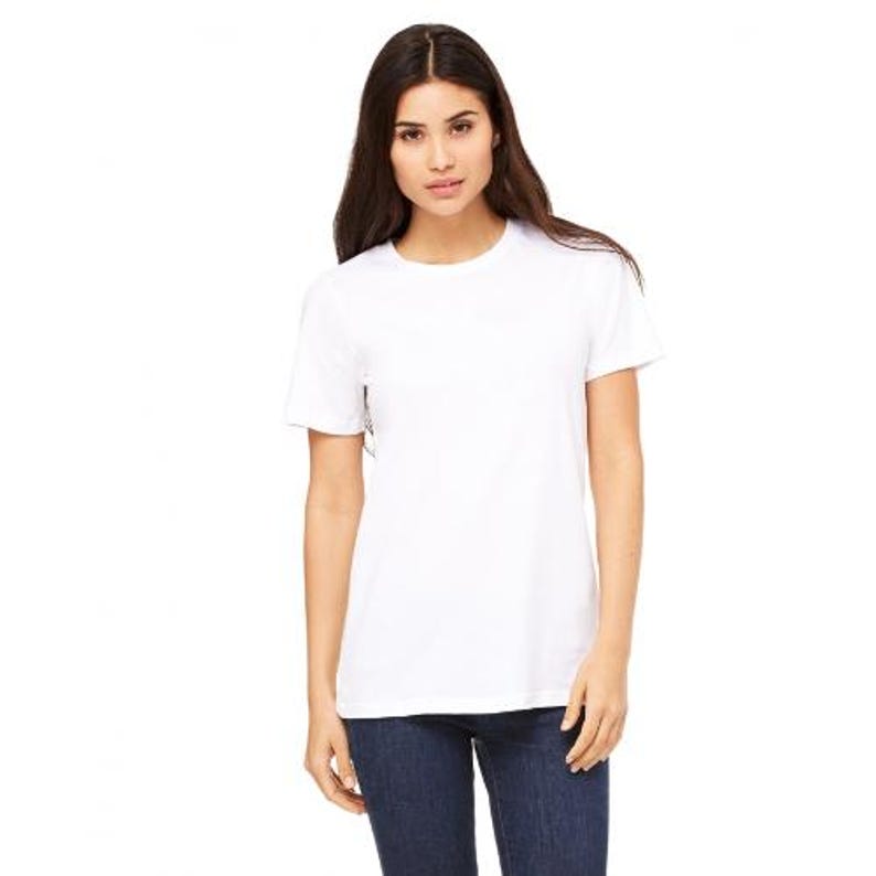 May include: A white crew neck t-shirt. The short-sleeved shirt is made of a soft material. The model is wearing dark blue jeans.