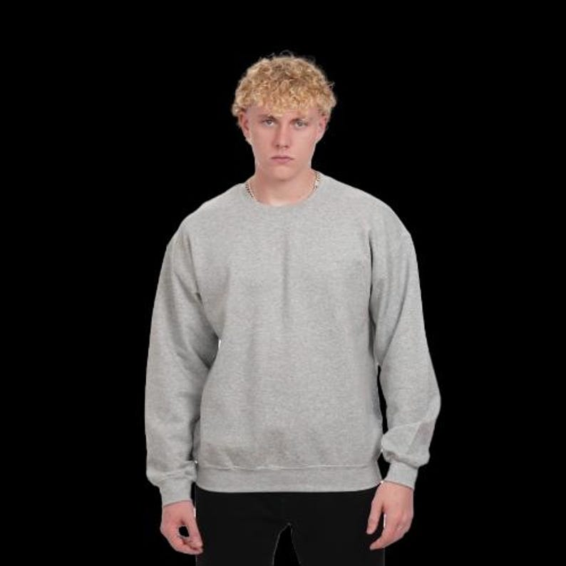 May include: A heather gray crew neck sweatshirt with long sleeves. The sweatshirt is a solid color and has a ribbed hem and cuffs. The model is wearing black pants.