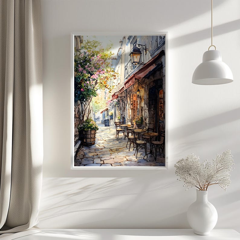 May include: A watercolor painting of a Parisian street scene with a cafe on the corner. The cafe has a red awning and tables and chairs set up outside. The street is cobblestone and there are trees and flowers lining the street.