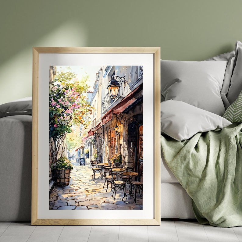 May include: A watercolor painting of a Parisian street scene with a cafe on the corner. The cafe has a red awning and a stone facade. There are tables and chairs set up outside the cafe, and a street lamp hangs above the entrance. The street is cobblestone and lined with trees and buildings.
