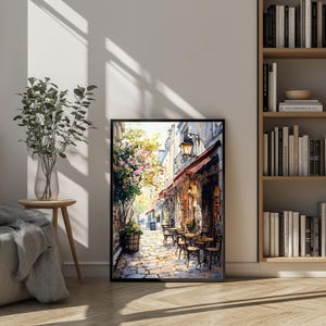 May include: A watercolor painting of a narrow street in a European city. The street is lined with buildings, and there are trees and flowers growing along the sides. There are tables and chairs set up outside a cafe, and people are sitting at the tables. The painting is done in a realistic style, and the colors are bright and vibrant.