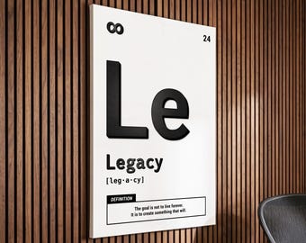 May include: A white rectangular wall art piece with the word "Le" in large, bold, black letters above the word "Legacy". The definition of legacy is included below the word. The wall art is mounted on a wooden wall.