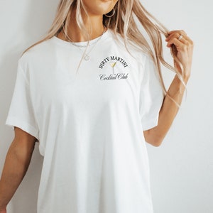 May include: White t-shirt with a black graphic that says "Dirty Martini Cocktail Club" and a martini glass illustration.