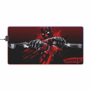 May include: A red and black gaming mouse pad featuring a graphic of Deadpool holding two guns. The background is red with black splatters. The text "DEADPOOL" is in the bottom right corner.