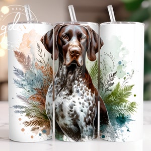 Puede incluir: Un vaso blanco con un diseño de acuarela de un perro Braco Alemán de Pelo Corto y follaje verde. El perro es marrón y blanco con la nariz negra y los ojos marrones. El vaso tiene una tapa transparente y una pajita.