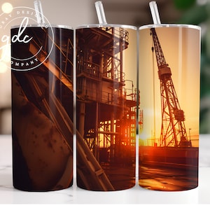 May include: Three stainless steel tumblers with a sunset scene featuring a large industrial crane and a factory in the background. The tumblers are all the same size and have a clear lid with a straw.