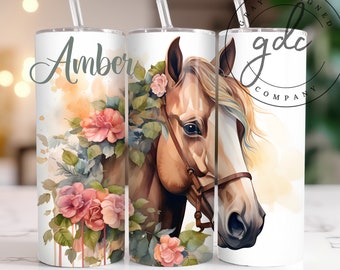 Puede incluir: Tres vasos blancos con un diseño de acuarela de una cabeza de caballo y rosas rosas. Los vasos tienen tapas transparentes y pajitas. El vaso de la izquierda tiene el nombre "Amber" escrito en él. El vaso de la derecha tiene el texto "Gray Designed Company" en él.