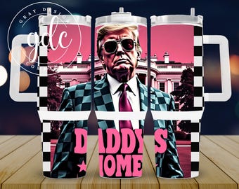 Puede incluir: Un vaso de acero inoxidable blanco con un patrón de cuadros blanco y negro y un gráfico rosa y blanco que dice "Daddy's Home". El vaso presenta un retrato de un hombre con gafas de sol y un traje a cuadros. El fondo es un degradado rosa y blanco con un edificio blanco.