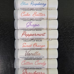 May include: A selection of eleven lip balms, each in a white tube with a flavour label. Flavours include "Unscented," "Skittles," and "Blue Raspberry." The ingredients are listed on each tube. The balms are for the lips.