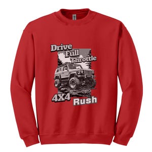 May include: A red sweatshirt featuring a graphic of a 4x4 vehicle on a rocky terrain. The design includes the text "Drive Full Throttle" and "4x4 Rush" in a stylized font. The sweatshirt is made of a soft material.