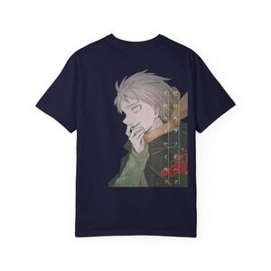 May include: A dark navy blue short-sleeve t-shirt featuring a graphic print of an anime-style character with light hair, wearing a green and orange garment. The design includes vertical Japanese text and red circular accents on the right side.