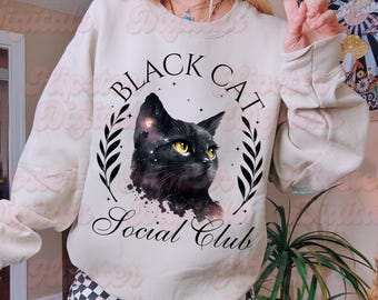 May include: A white sweatshirt with a black cat graphic and the text "Black Cat Social Club".