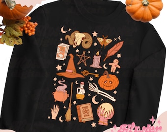 Op de afbeelding: Zwart sweatshirt met een wit en oranje ontwerp met een tovenaarshoed, een ketel, een pompoen, een schedel, een tarotkaart, een kristallen bol, een magisch boek, een veer, een ster, een sleutel, een kaars, een bezem en een wassende maan. De tekst "Magic Book" staat op het boek gedrukt.