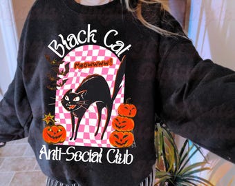 May include: Black sweatshirt with a Halloween-themed graphic. The design features a black cat with a pink and white checkered background, pumpkins, and the text "Black Cat Anti-Social Club". Bats and a star are also included in the design.