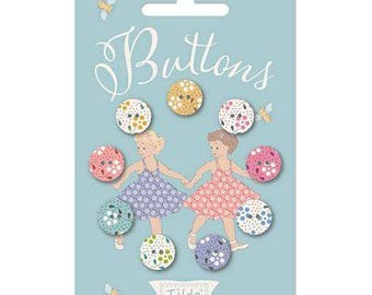 Könnte beinhalten: Eine hellblaue Karte mit dem Wort "Buttons" in Schreibschrift. Die Karte zeigt eine Sammlung dekorativer Knöpfe mit floralen Mustern und Illustrationen von zwei Mädchen, die sich an den Händen halten. Der Markenname "Tilda" ist ebenfalls sichtbar.
