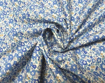 May include: White fabric with a blue and pink floral pattern. The fabric is folded and has a soft, crinkled texture.