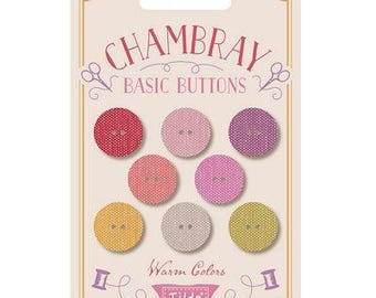 Könnte beinhalten: Eine Packung Chambray Basic Knöpfe in warmen Farben. Die Karte zeigt sieben runde Knöpfe in Rot-, Rosa-, Lila-, Gelb- und Grautönen. Die Karte trägt den Text "Chambray Basic Buttons" und "Warm Colors" mit dem Markennamen "Tilda".