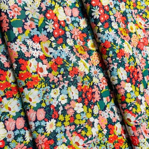 May include: A navy blue fabric with a floral print featuring a variety of pink, red, yellow, and white flowers. The fabric is perfect for crafting projects, quilting, and sewing.