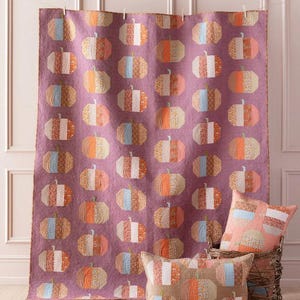 May include: A quilt with a pattern of orange, pink, and blue pumpkins on a purple background. There are three matching pillow covers with the same pumpkin pattern.