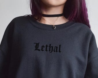 May include: A dark grey sweatshirt with the word "Lethal" embroidered in black on the front. The sweatshirt has a relaxed fit and a crew neck.