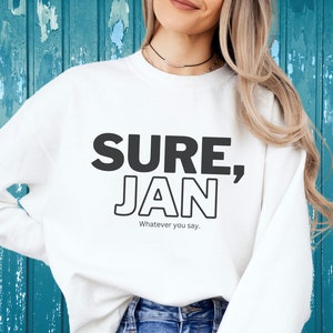 May include: White sweatshirt with black text that reads "SURE, JAN" and "Whatever you say."