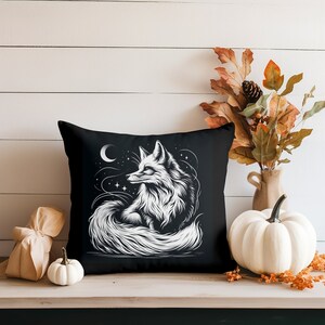 May include: Black throw pillow with a white illustration of a fox curled up with its tail around its body. The fox is surrounded by stars and a crescent moon.
