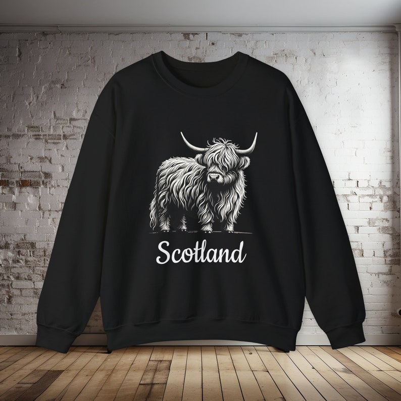 Puede incluir: Sudadera negra con un gr&aacute;fico blanco de una vaca de las tierras altas y la palabra "Escocia" impresa debajo.