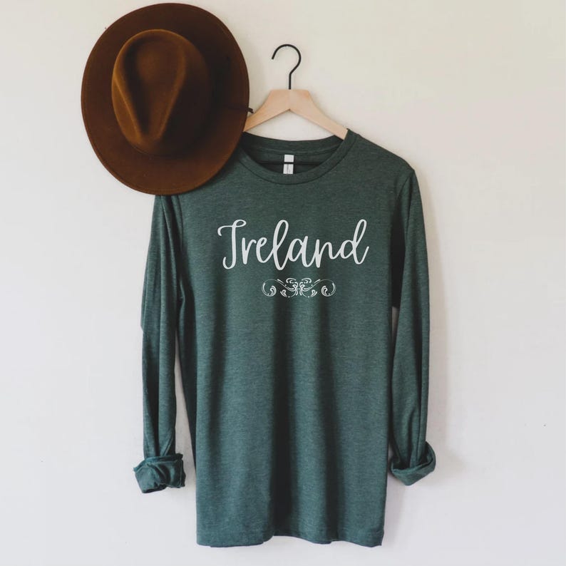 May include: A dark green long-sleeved t-shirt with the word "Ireland" printed in white cursive lettering.