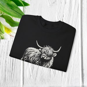 Puede incluir: Camiseta negra con un gr&aacute;fico blanco de una vaca Highland con pelo largo y peludo.