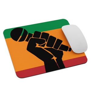 May include: A black fist holding a microphone, with a green, orange, and red background. The colors are reminiscent of the Pan-African flag.