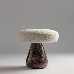 May include: A contemporary stool featuring a white, textured, oval seat atop a dark brown, marble-effect base. The base is shaped like an inverted cone. This stool is a decorative furniture item.