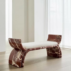 Könnte beinhalten: Moderner Hocker mit roter Marmorbasis und weißem, strukturiertem Sitz. Der Hocker hat ein geschwungenes Design mit poliertem Finish, das die natürliche Maserung des Marmors hervorhebt. Die Gesamtästhetik ist modern und luxuriös.