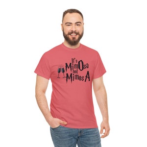 May include: A coral-coloured t-shirt featuring the text "It's Mimosa not MimosA" in black, accompanied by two champagne flutes. This is a casual wear item.