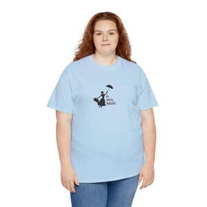 May include: A light blue t-shirt with a black silhouette of a woman holding an umbrella and the text "In omnia paratus".