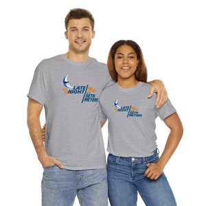 Puede incluir: Dos personas con camisetas grises de mezcla con un gráfico azul y naranja de una luna creciente con gafas de sol y el texto "Late Night with Seth Meyers".