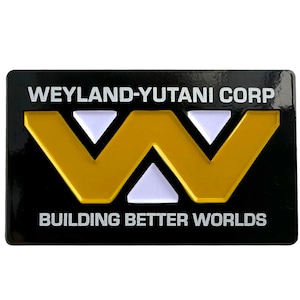Könnte beinhalten: Schwarz-goldenes Weyland-Yutani Corp. Logo mit dem Text "Building Better Worlds".