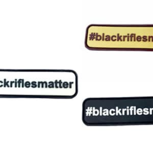 May include: Three rectangular patches with the text "#blackriflesmatter" in black lettering on a white, beige, and black background.